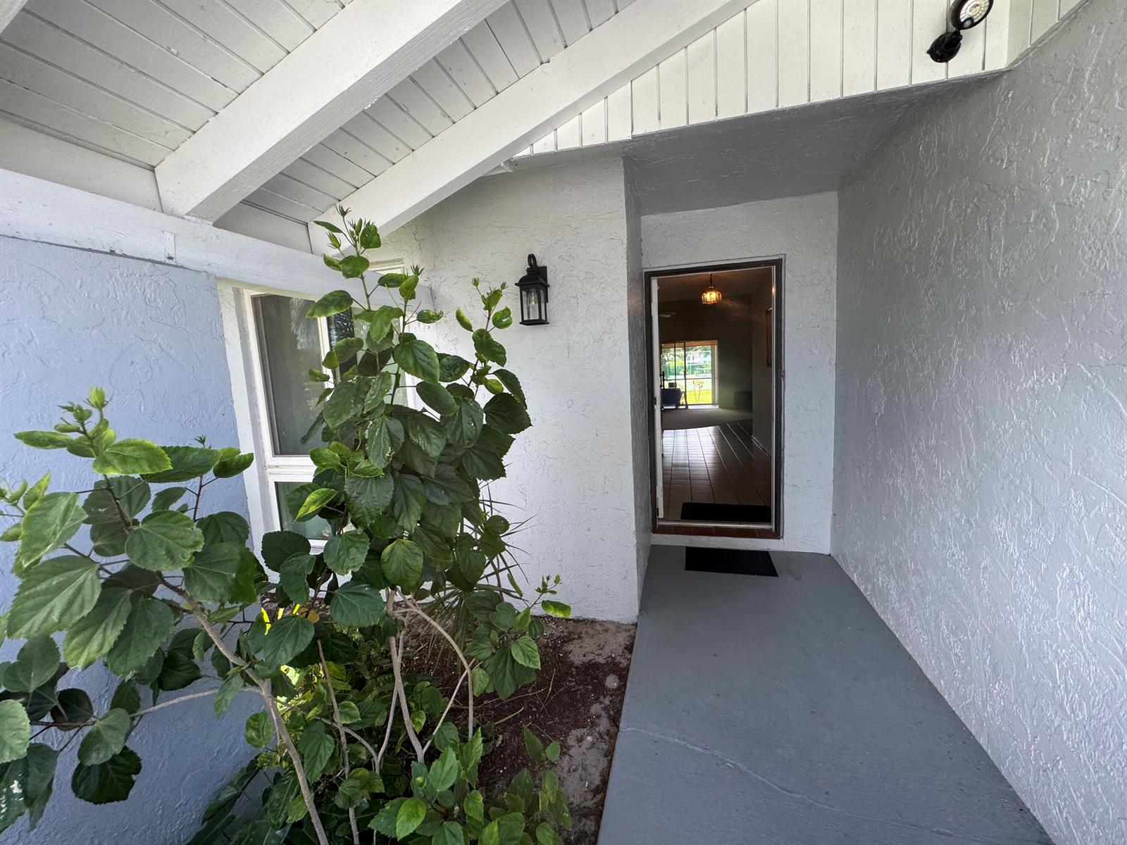 A covered entryway features a grey concrete porch, a white exterior, and a front door — 744 Lago Road # 1f, Delray Beach FL 33445, DELRAY BEACH, FL