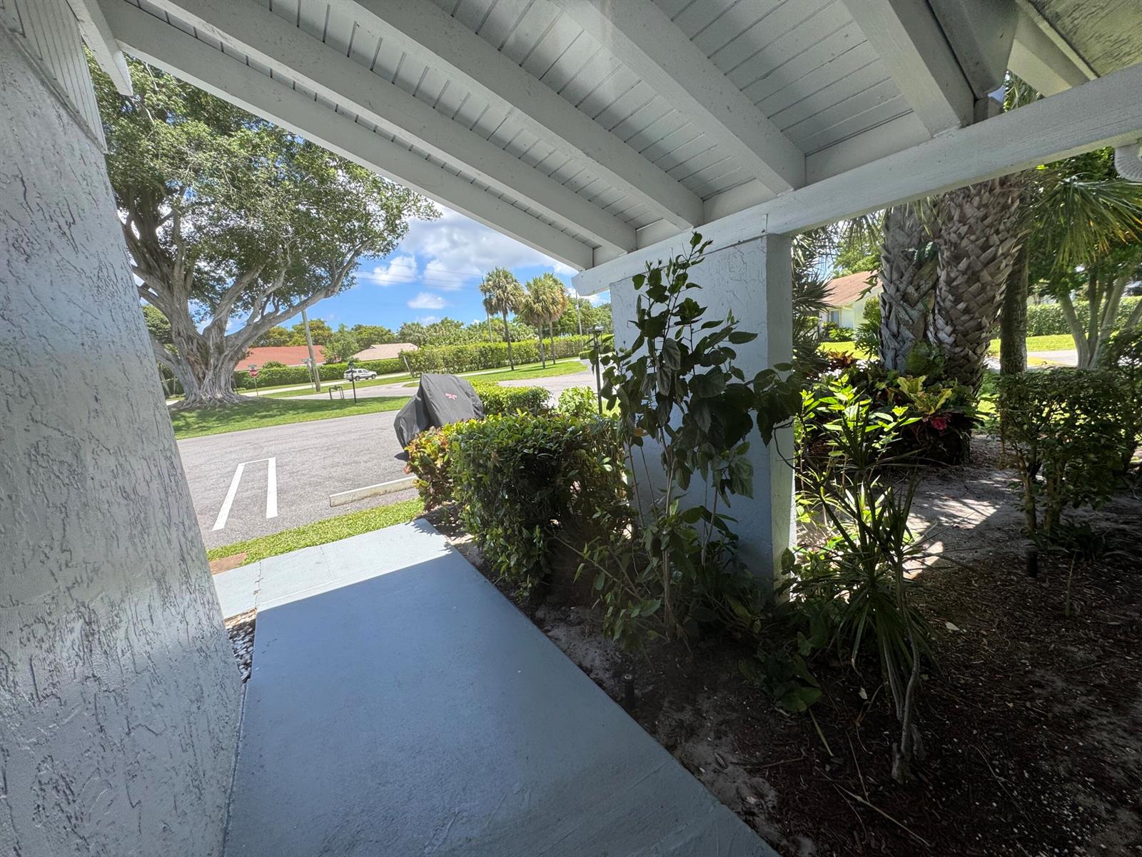 A covered entryway with a painted concrete floor leads to a landscaped yard and parking — 744 Lago Road # 1f, Delray Beach FL 33445, DELRAY BEACH, FL
