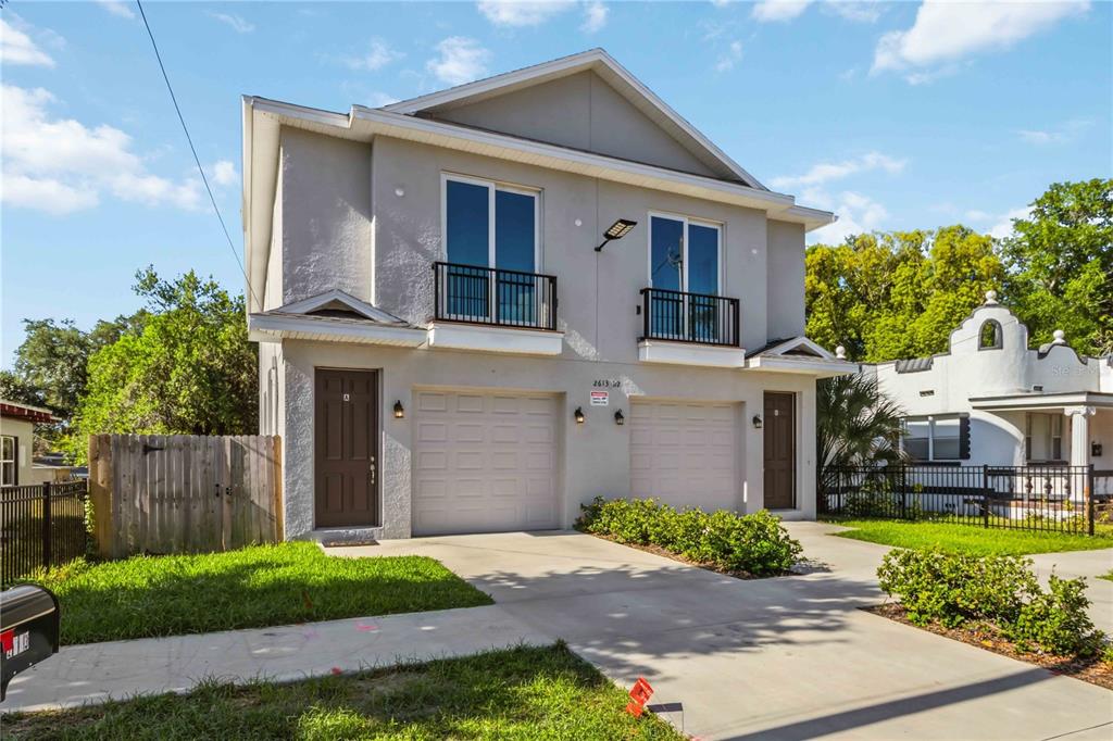 A two-story duplex with a gray stucco exterior, two garages, and two front entry doors — 2613 E 23RD AVENUE UNIT 1/2, TAMPA, FL
