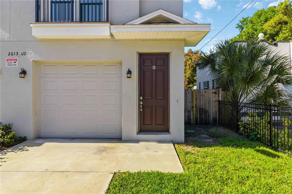 The exterior of a building features a garage, a brown door, and a small lawn — 2613 E 23RD AVENUE UNIT 1/2, TAMPA, FL