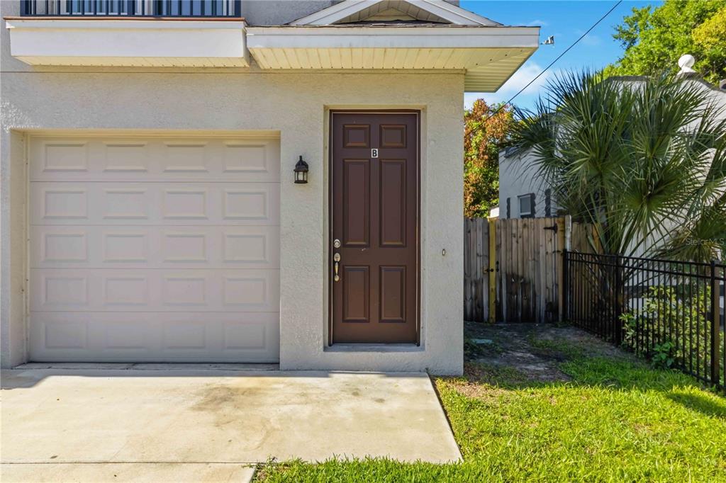 A beige exterior features a single-car garage, a brown front door labeled B, and landscaping — 2613 E 23RD AVENUE UNIT 1/2, TAMPA, FL