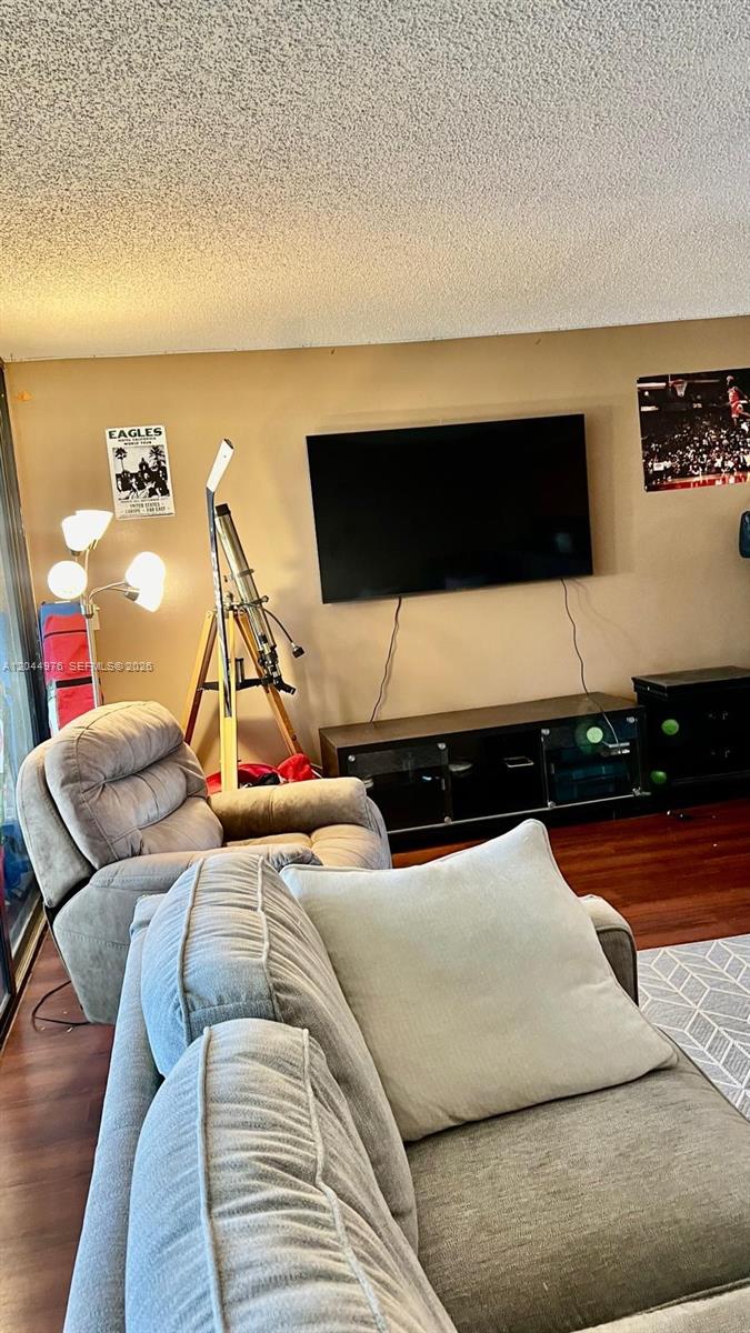A living room features a wall-mounted television, a telescope, and a recliner — 8711 SW 30th St # 106, Davie FL 33328, DAVIE, FL