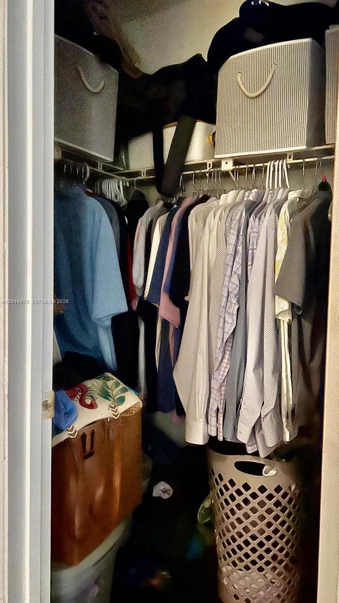 A closet is filled with hanging clothes, storage bins on a shelf, and a laundry basket — 8711 SW 30th St # 106, Davie FL 33328, DAVIE, FL