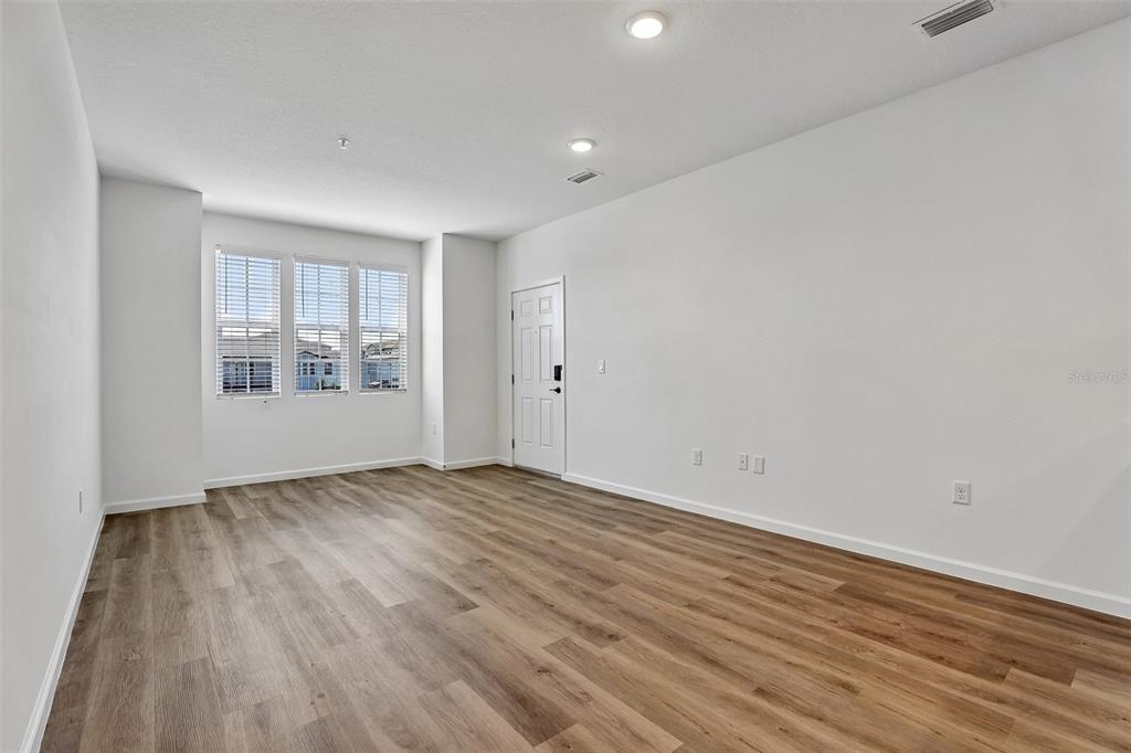 An empty room with white walls, wood-look flooring, recessed lighting, and three windows — 3075 SOLDIER CITY WAY UNIT 201, ST CLOUD, FL