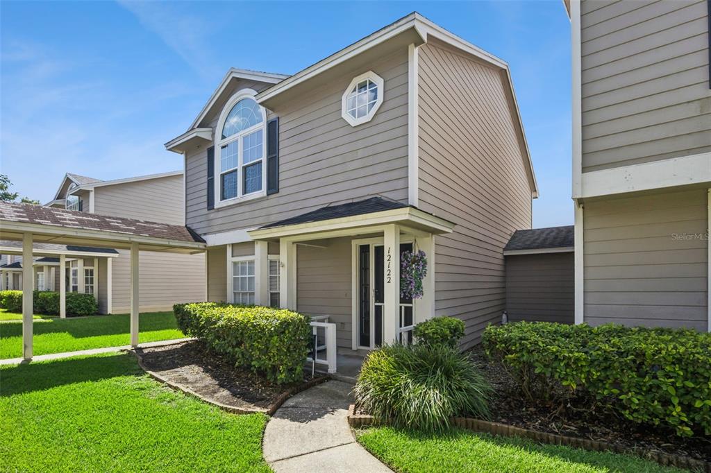 A two-story house with gray siding, a covered walkway, and a small front garden — 12122 BRUCETON WAY UNIT 103, ORLANDO, FL