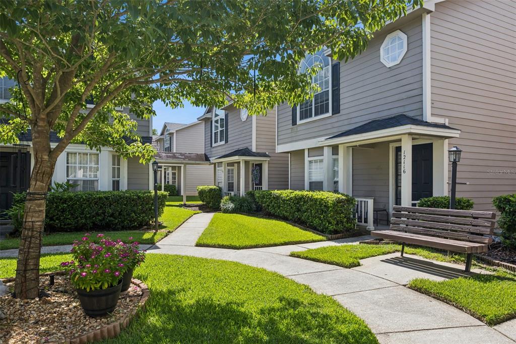 A wooden bench sits on a concrete walkway in front of a two-story townhouse exterior — 12122 BRUCETON WAY UNIT 103, ORLANDO, FL