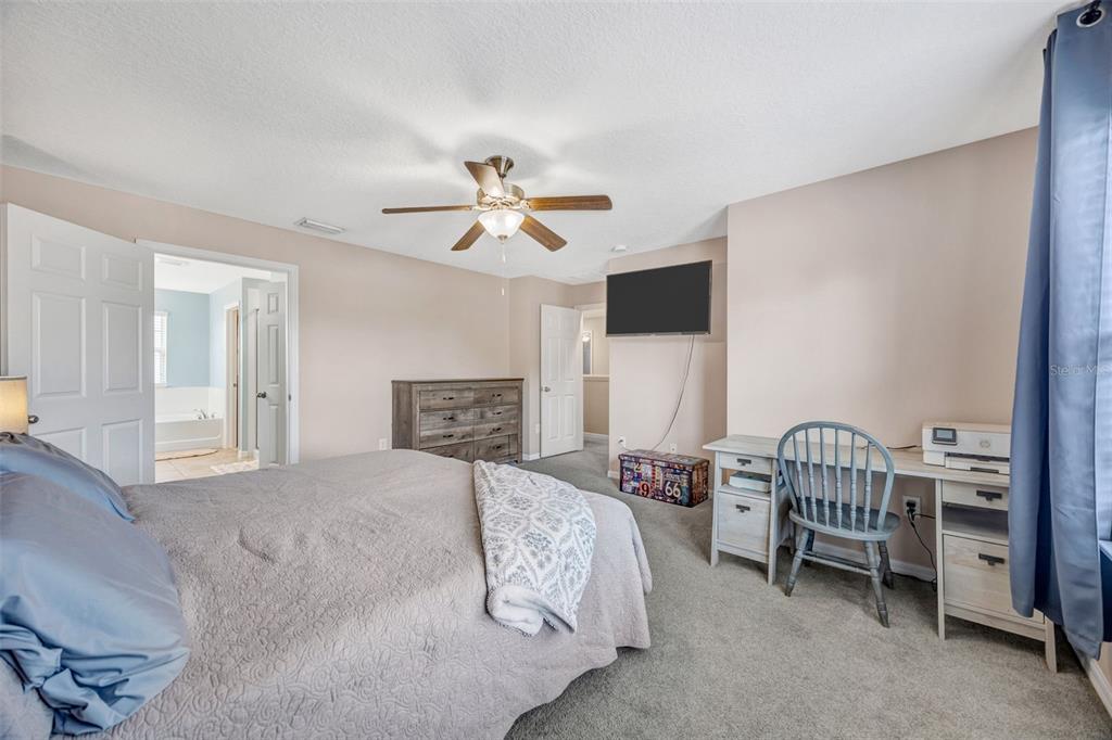 A bedroom features a bed, a wooden dresser, a desk with a chair, and an ensuite bathroom — 5420 ANGELONIA TERRACE, LAND O LAKES, FL