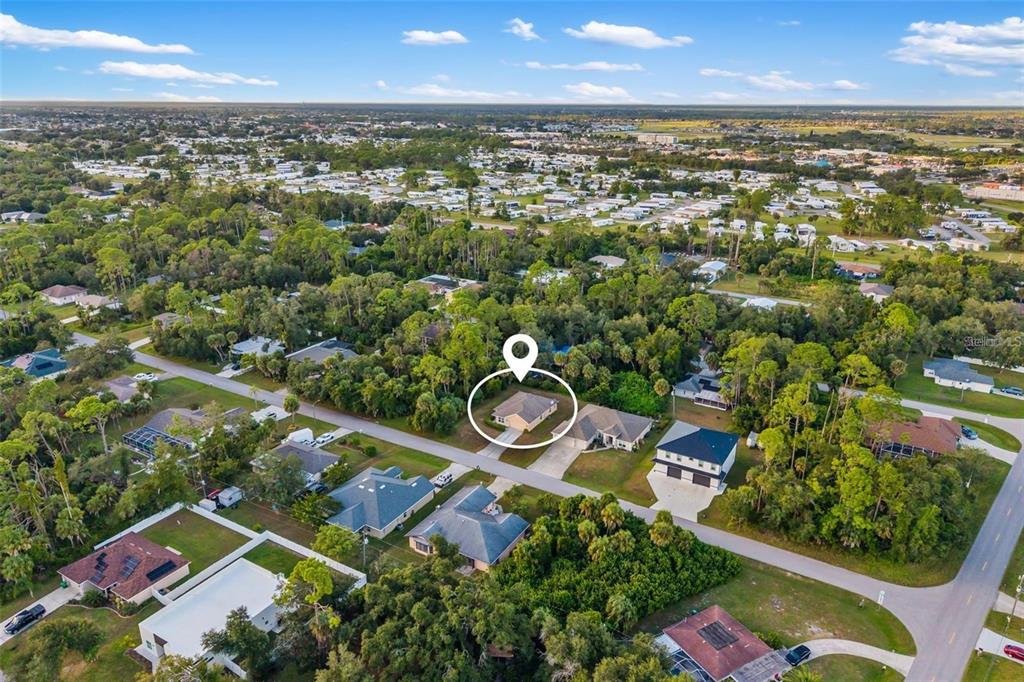 An aerial view shows a single-story house highlighted by a location marker in a neighborhood — 13558 GOODRICH AVENUE, PORT CHARLOTTE, FL