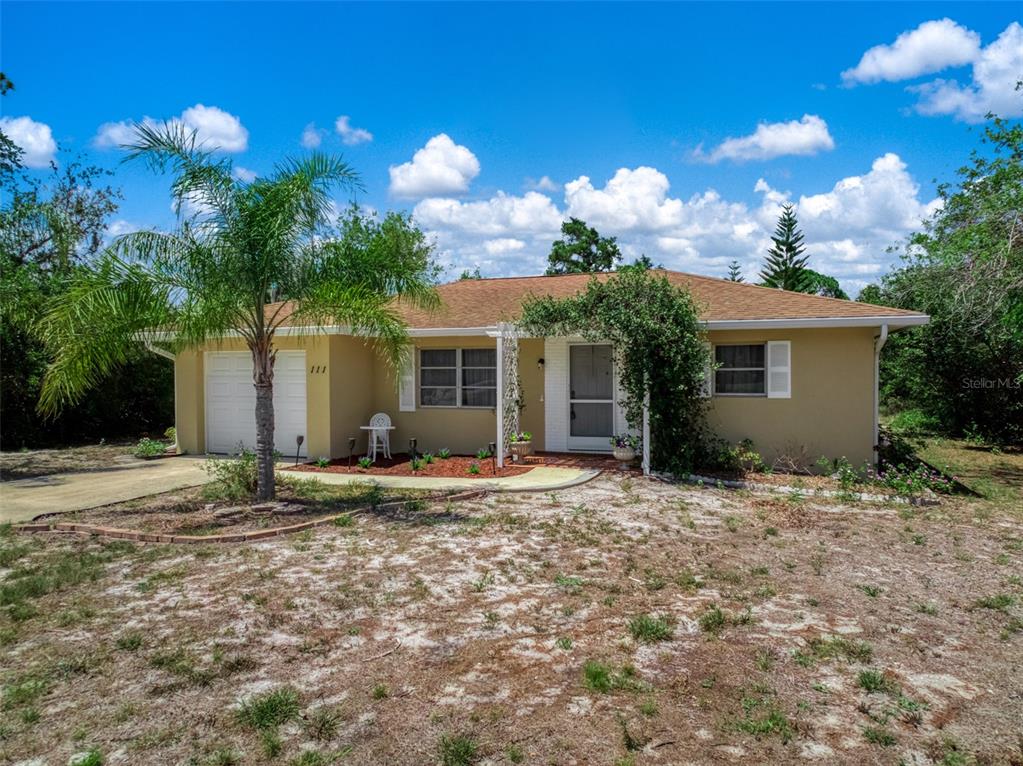 A single-story house with a tan exterior, a garage, and a palm tree in front — 111 LEMON ROAD NW, LAKE PLACID, FL