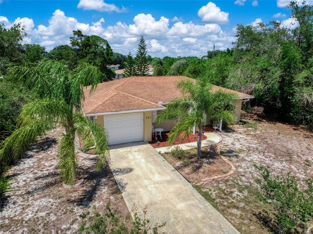 An aerial view of a single-story house with a tan roof and a concrete driveway — 111 LEMON ROAD NW, LAKE PLACID, FL