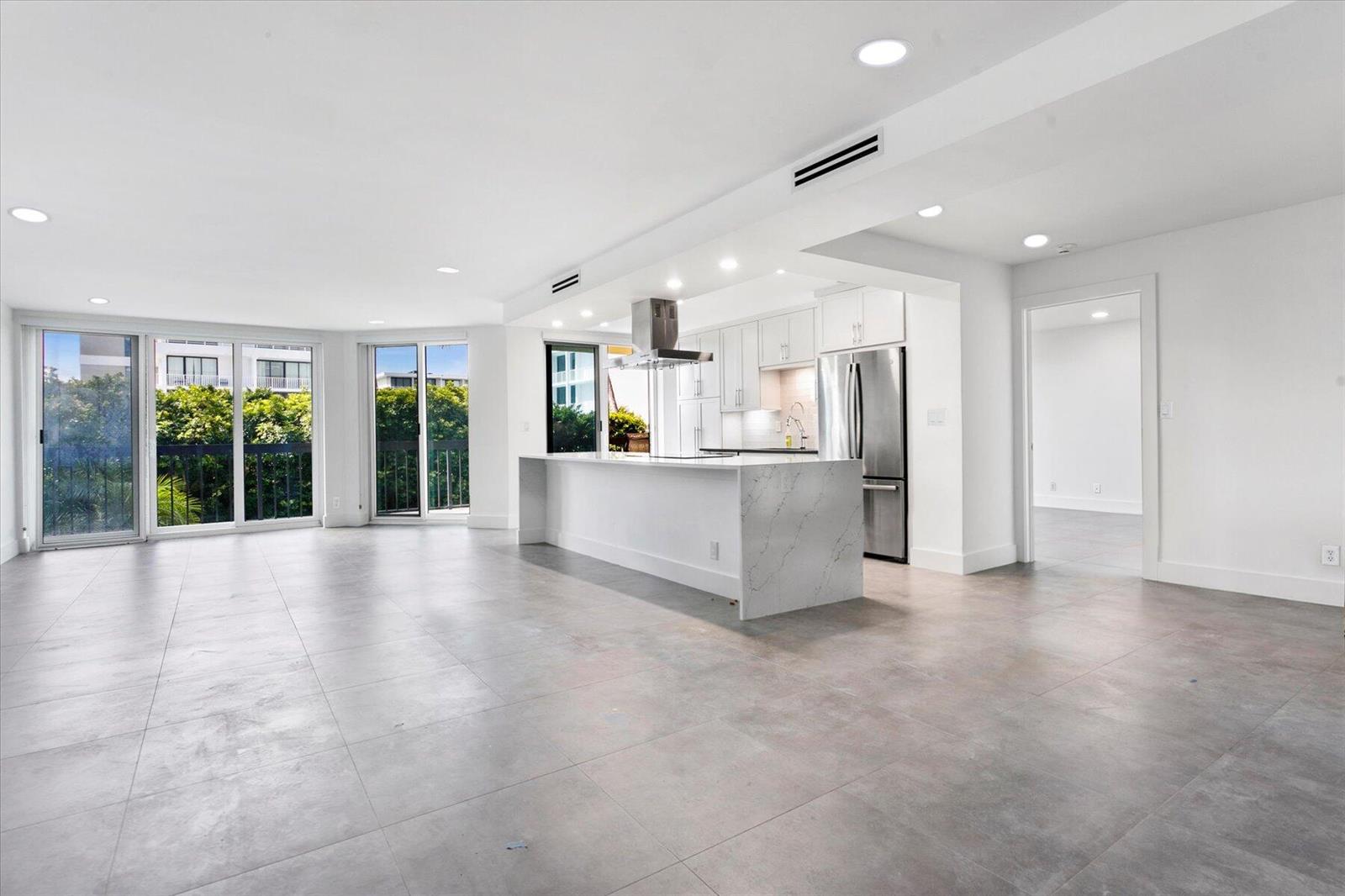 A modern bedroom features a white tufted bed, blue accents, and a sliding glass balcony door — 2778 S Ocean Boulevard # 203s, Palm Beach FL 33480, PALM BEACH, FL