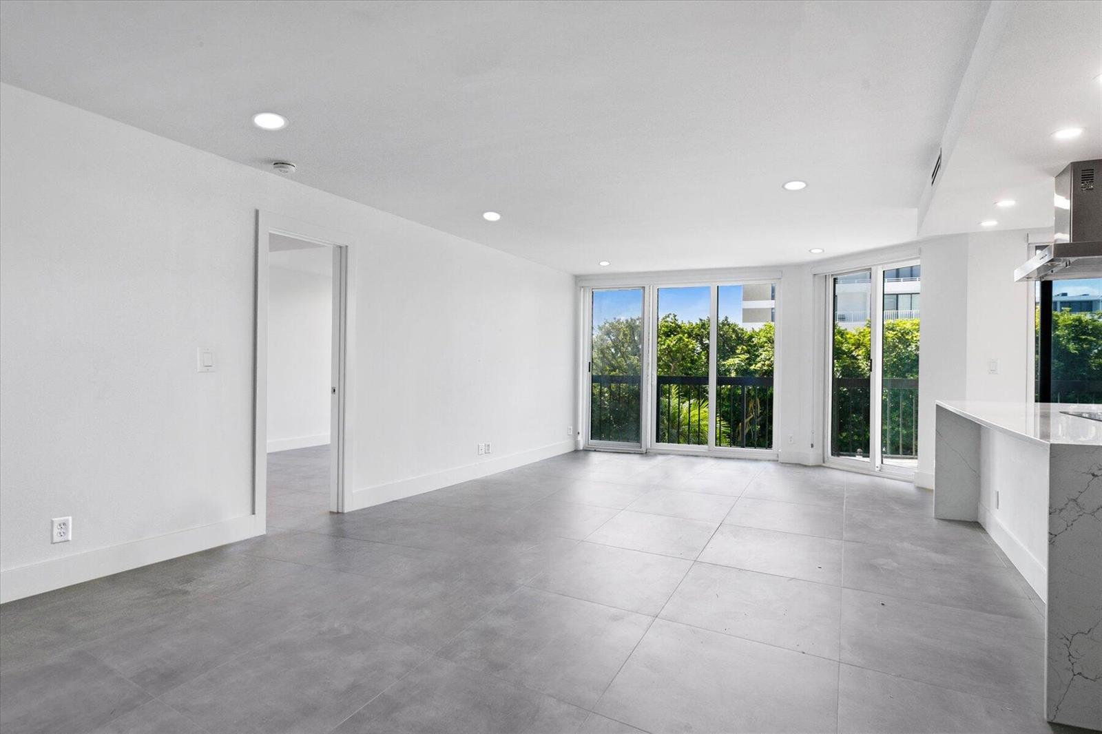A modern open-concept kitchen and living area with white cabinetry, marble countertops, and tiled floors — 2778 S Ocean Boulevard # 203s, Palm Beach FL 33480, PALM BEACH, FL