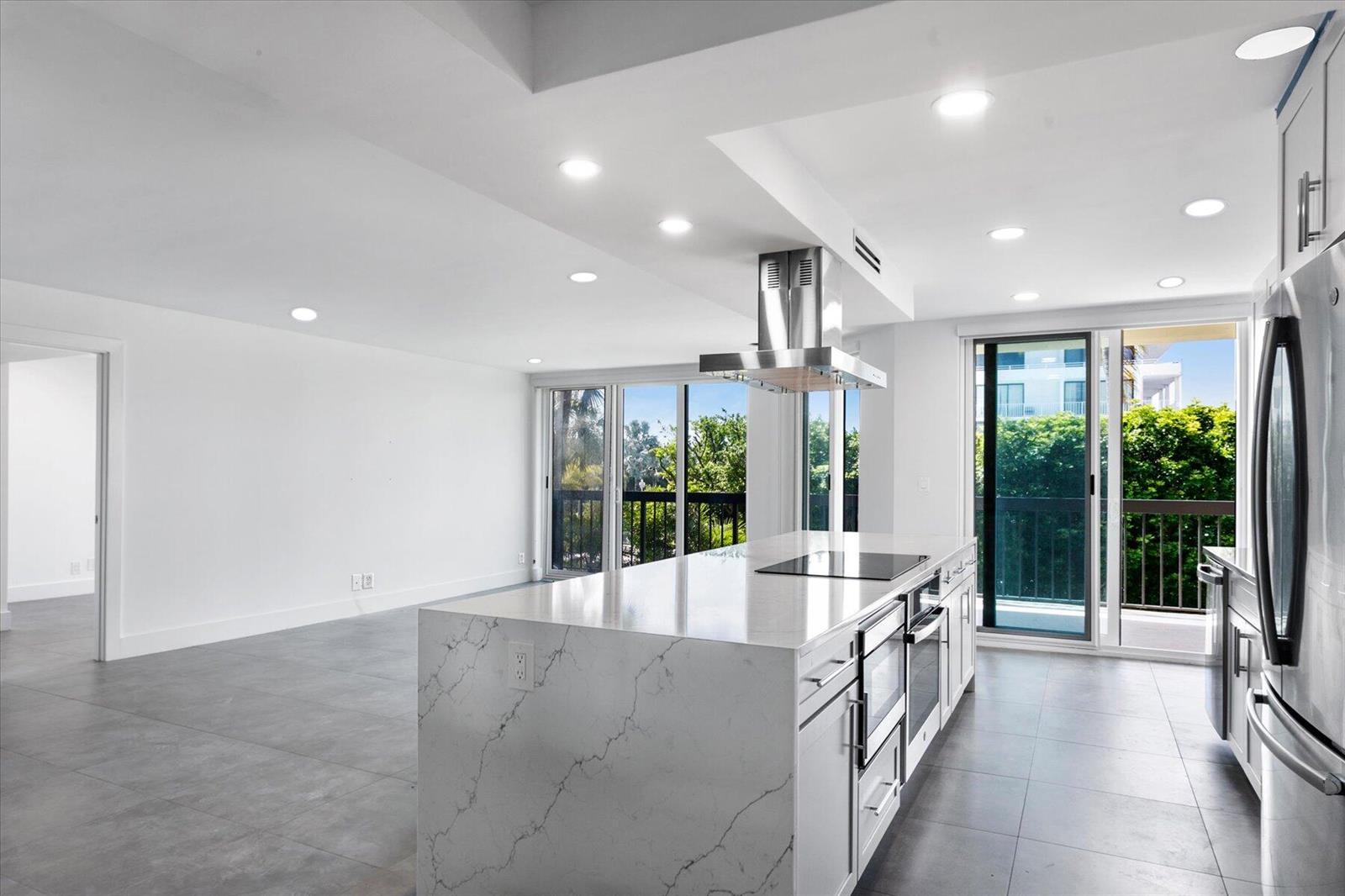 A hallway with two white doors leads to a modern kitchen with a marble island — 2778 S Ocean Boulevard # 203s, Palm Beach FL 33480, PALM BEACH, FL
