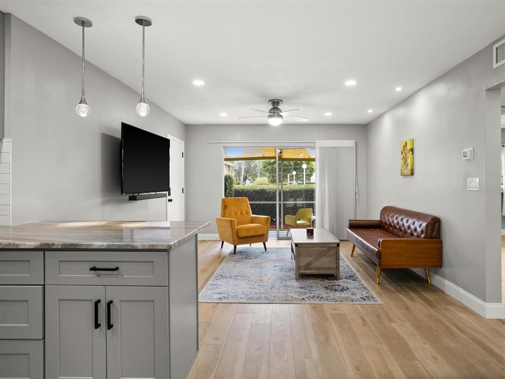 A living room with a brown leather sofa, yellow armchair, area rug, and sliding glass doors — 8303 BARDMOOR BOULEVARD UNIT 105, SEMINOLE, FL
