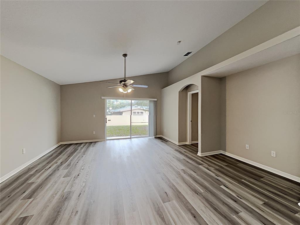 A living room features vaulted ceilings, wood-look flooring, and a sliding glass door to outside — 3053 EGRETS LANDING DRIVE, LAKE MARY, FL