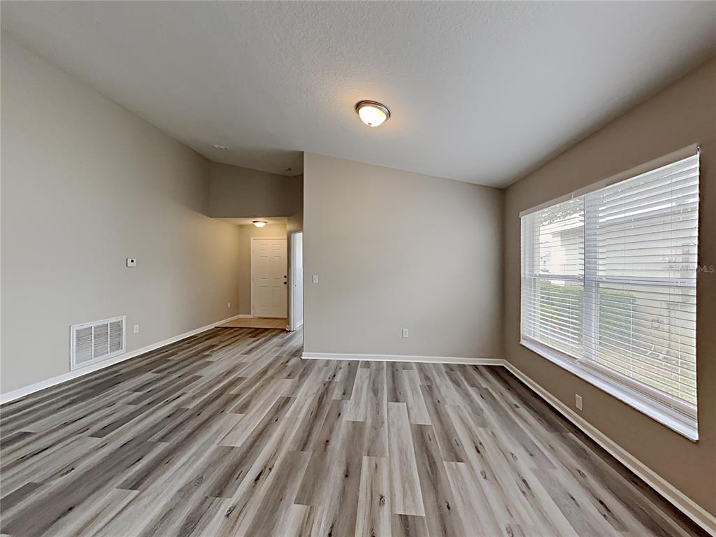 An empty room features light-colored walls, wood-look flooring, a ceiling light, and a large window — 3053 EGRETS LANDING DRIVE, LAKE MARY, FL
