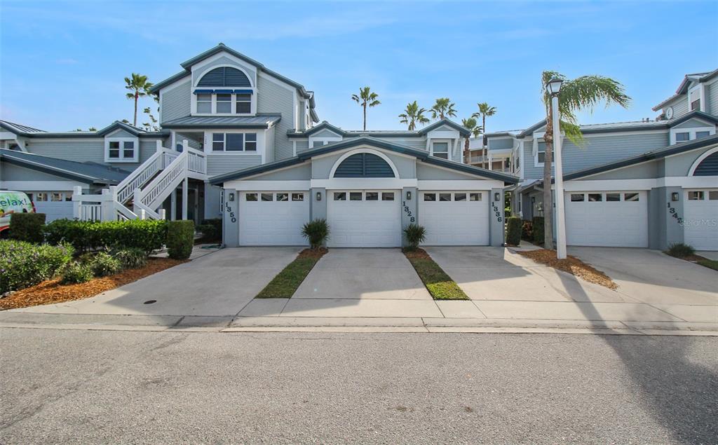 A row of multi-story townhomes features white garage doors and light blue siding — 1328 SIESTA BAYSIDE DRIVE UNIT 1328-C, SARASOTA, FL