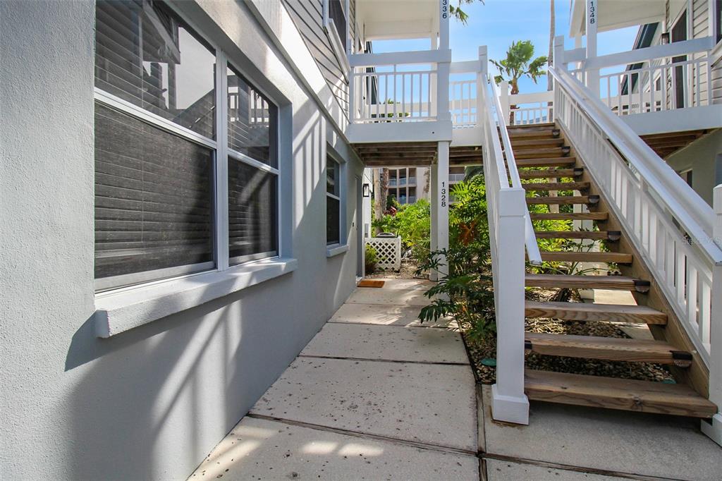 A concrete walkway leads to an outdoor staircase and a building entrance with gray siding — 1328 SIESTA BAYSIDE DRIVE UNIT 1328-C, SARASOTA, FL