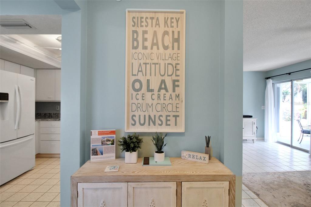 A light blue entryway features a wooden console table topped with decor and a wall sign — 1328 SIESTA BAYSIDE DRIVE UNIT 1328-C, SARASOTA, FL