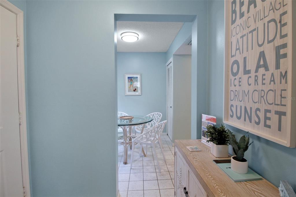 A light blue hallway leads to a dining area with a glass table and white chairs — 1328 SIESTA BAYSIDE DRIVE UNIT 1328-C, SARASOTA, FL