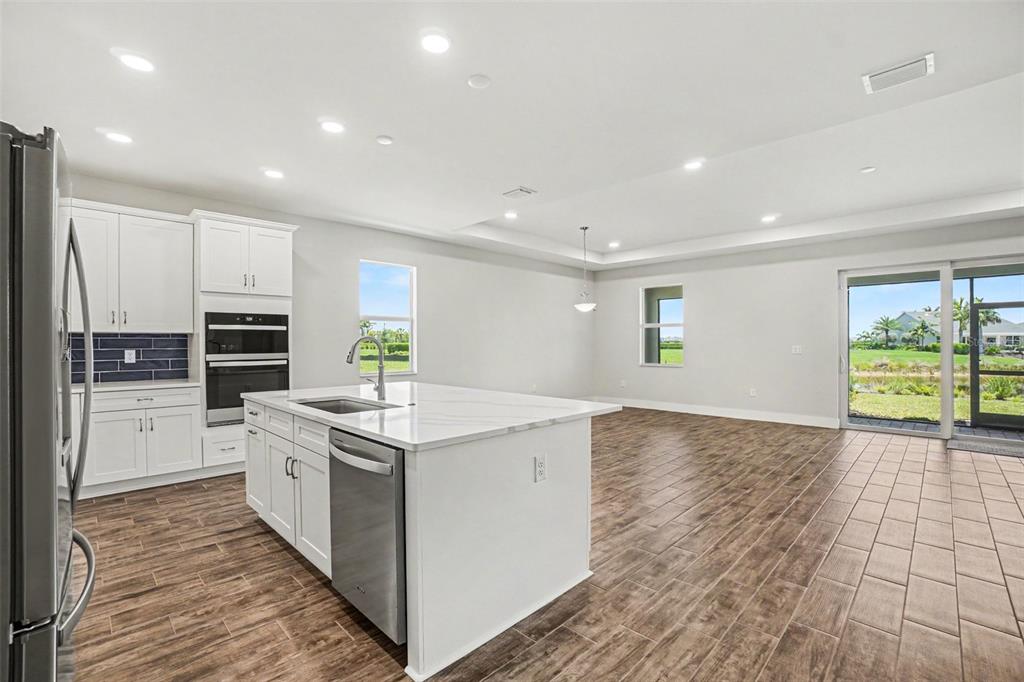 A modern kitchen features white cabinets, a central island, and tile flooring overlooking a backyard — 44353 PANTHER DRIVE, PUNTA GORDA, FL