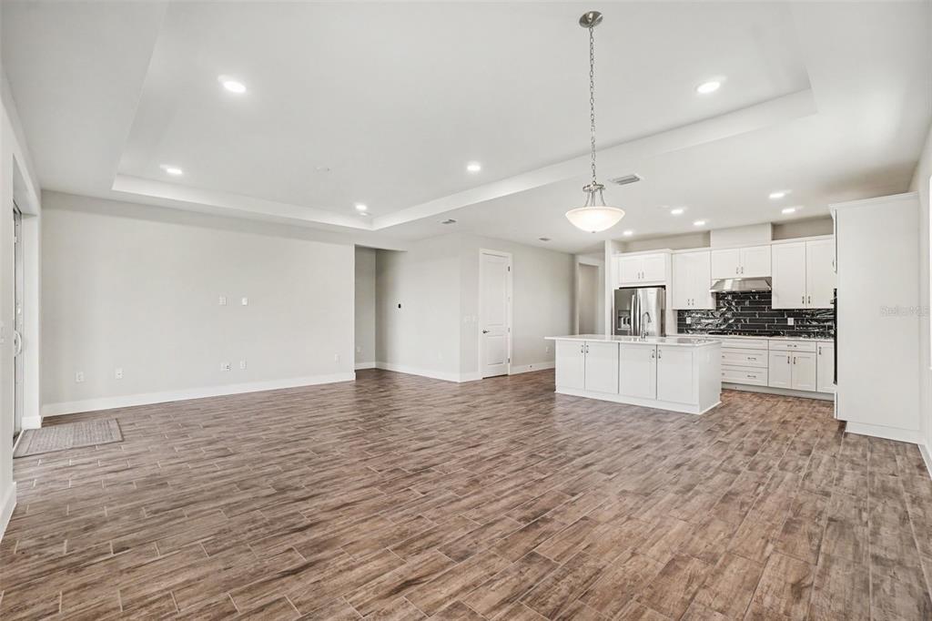An open-concept kitchen and living area featuring white cabinetry, a kitchen island, and wood-look flooring — 44353 PANTHER DRIVE, PUNTA GORDA, FL