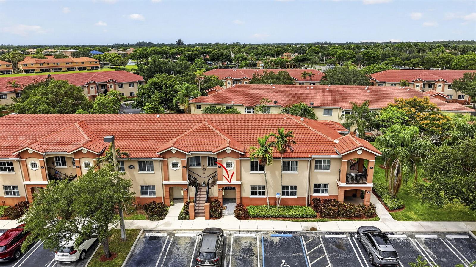 An exterior view of a multi-story apartment building with a red tile roof — 3501 Briar Bay Boulevard # 105, West Palm Beach FL 33411, WEST PALM BEACH, FL