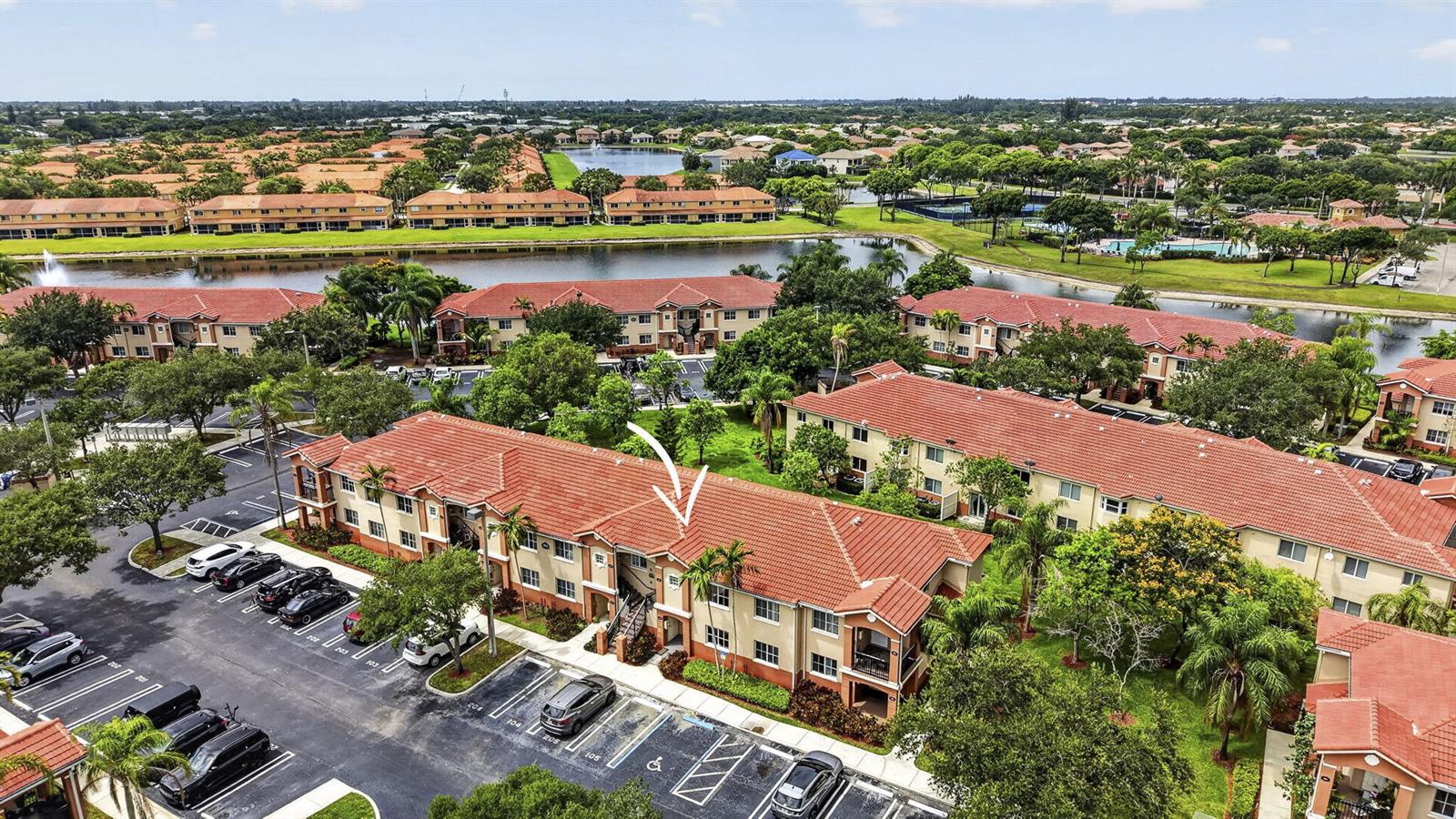An aerial view of a multi-story apartment complex with red tile roofs and parking lots — 3501 Briar Bay Boulevard # 105, West Palm Beach FL 33411, WEST PALM BEACH, FL