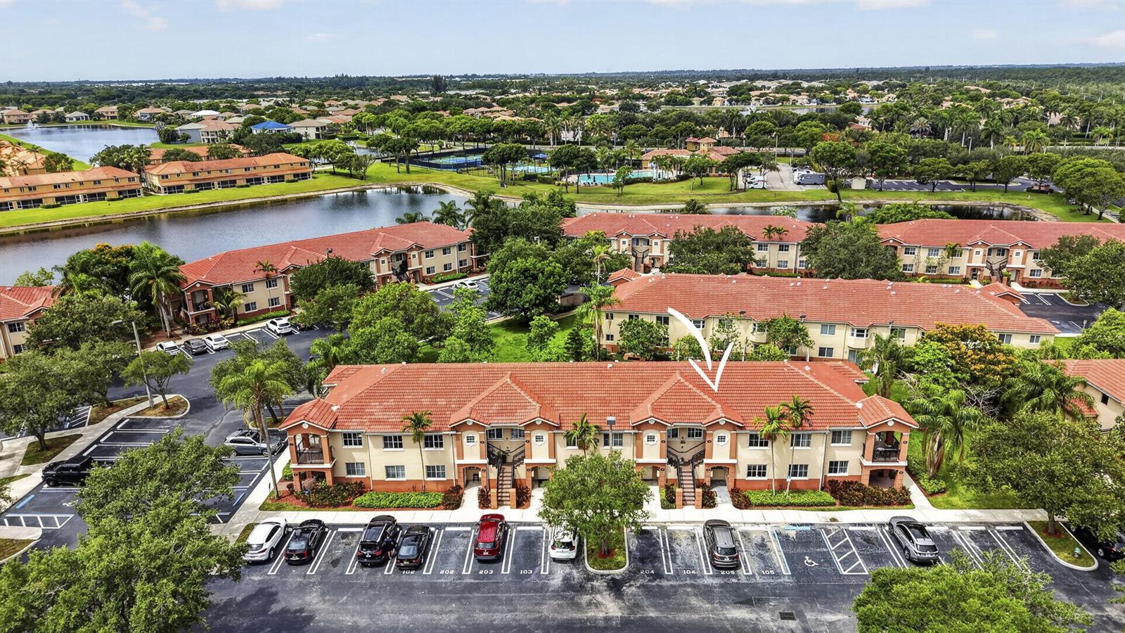 An aerial view shows a two-story apartment building with a red tile roof and parking — 3501 Briar Bay Boulevard # 105, West Palm Beach FL 33411, WEST PALM BEACH, FL