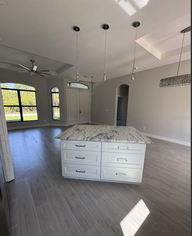 A kitchen island with white cabinets and a marble countertop sits in a spacious room — 342 KINDRED BOULEVARD, PORT CHARLOTTE, FL