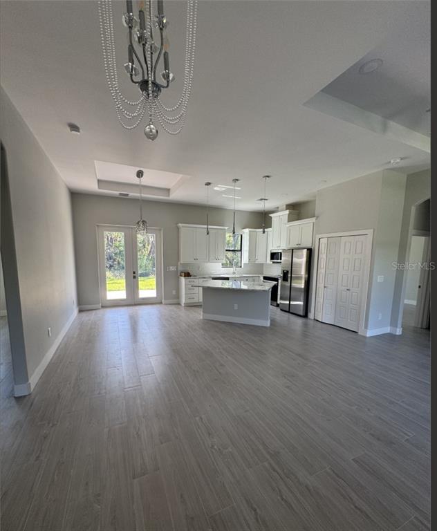 An open-concept kitchen and living area features white cabinetry, stainless steel appliances, and wood-look tile — 342 KINDRED BOULEVARD, PORT CHARLOTTE, FL