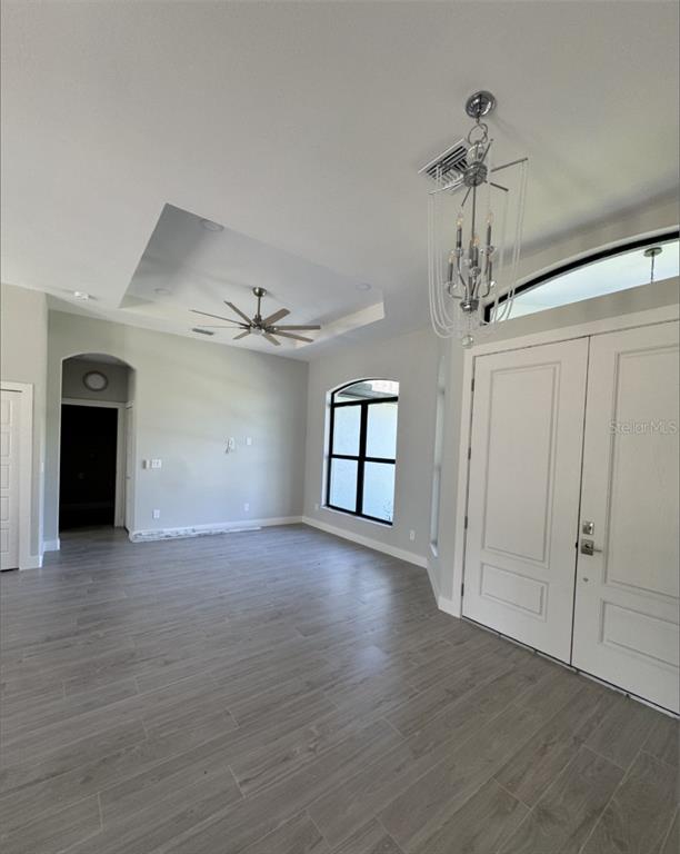 A bright living area features gray wood-look tile flooring, a tray ceiling, and a chandelier — 342 KINDRED BOULEVARD, PORT CHARLOTTE, FL