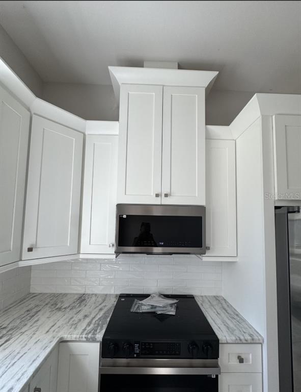 A kitchen features white shaker cabinets, a stainless steel microwave, and a marble-patterned countertop — 342 KINDRED BOULEVARD, PORT CHARLOTTE, FL