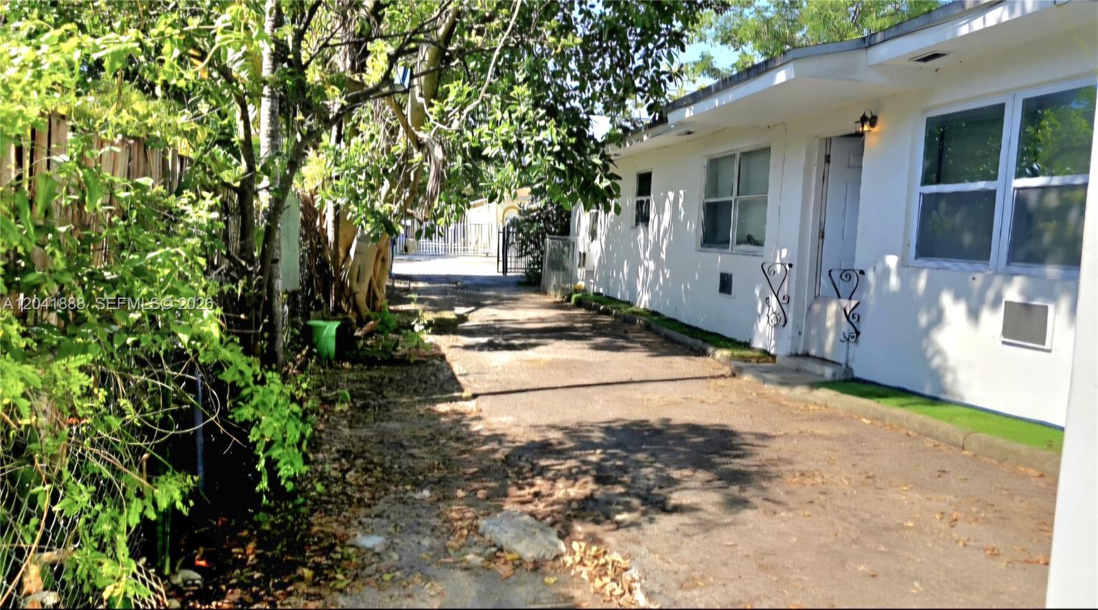 A paved driveway runs alongside a white exterior wall of a single-story building — 241 NW 32nd St, Miami FL 33127, MIAMI, FL