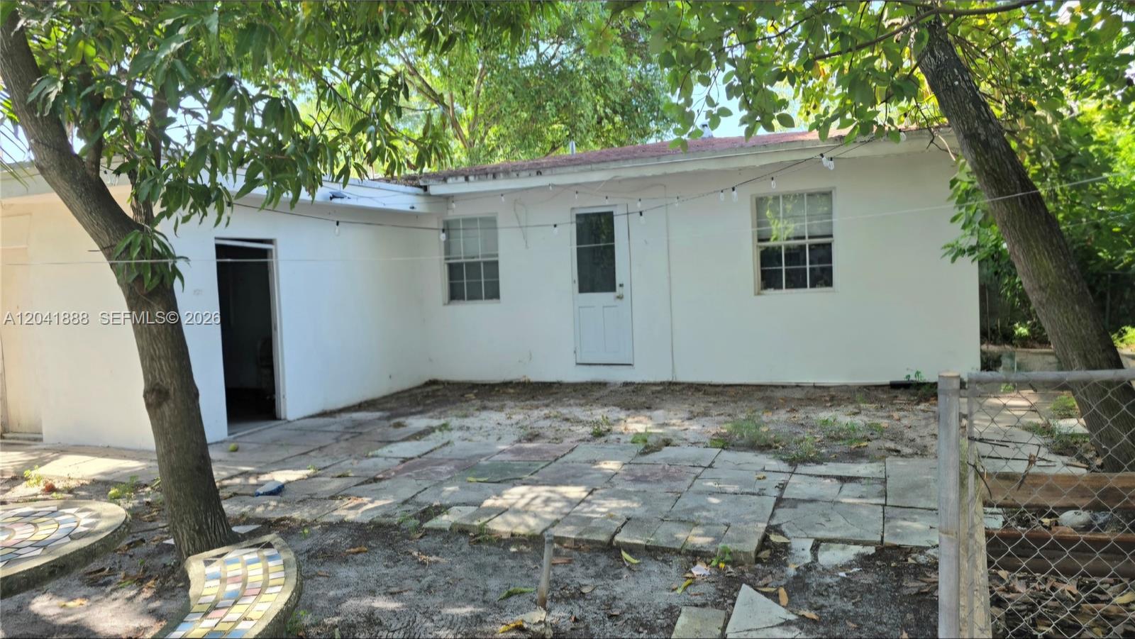 The exterior of a white house features a patio with stone pavers and a door — 241 NW 32nd St, Miami FL 33127, MIAMI, FL