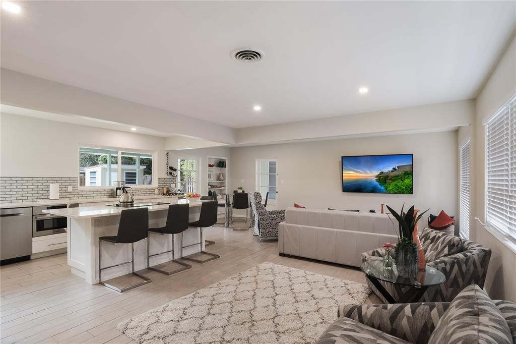 An open-concept kitchen and living area features a white island, stainless appliances, and neutral decor — 2266 CLEMATIS STREET, SARASOTA, FL