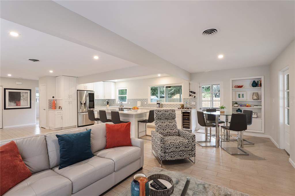An open-concept living room and kitchen featuring a gray sofa, patterned armchair, and dining area — 2266 CLEMATIS STREET, SARASOTA, FL