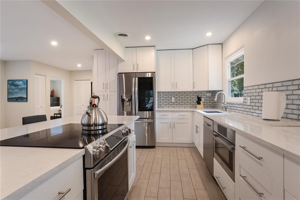 A modern kitchen features white cabinets, stainless steel appliances, a center island, and subway tile — 2266 CLEMATIS STREET, SARASOTA, FL