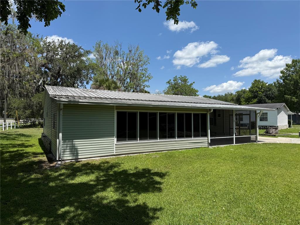 A light green house with a metal roof and a large screened-in porch — 26 CANAL WAY, LAKE PANASOFFKEE, FL