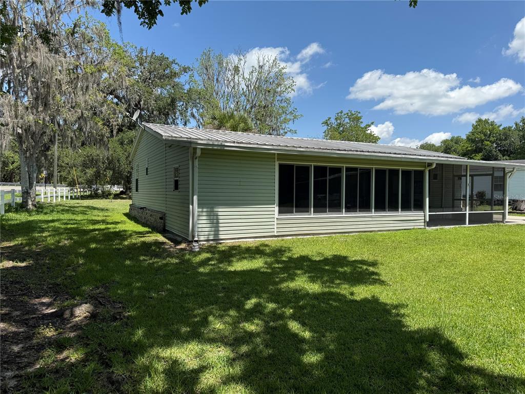 A light green house with a metal roof and a large screened-in porch — 26 CANAL WAY, LAKE PANASOFFKEE, FL