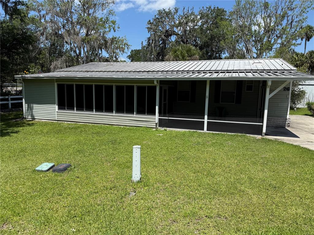 A single-story house with a metal roof, screened-in porch, and light-colored siding — 26 CANAL WAY, LAKE PANASOFFKEE, FL