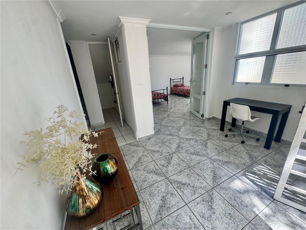 A room with gray tile flooring features a desk, a doorway, and a side hallway — 125 HARBOUR DRIVE UNIT 8, HUMACAO, PR