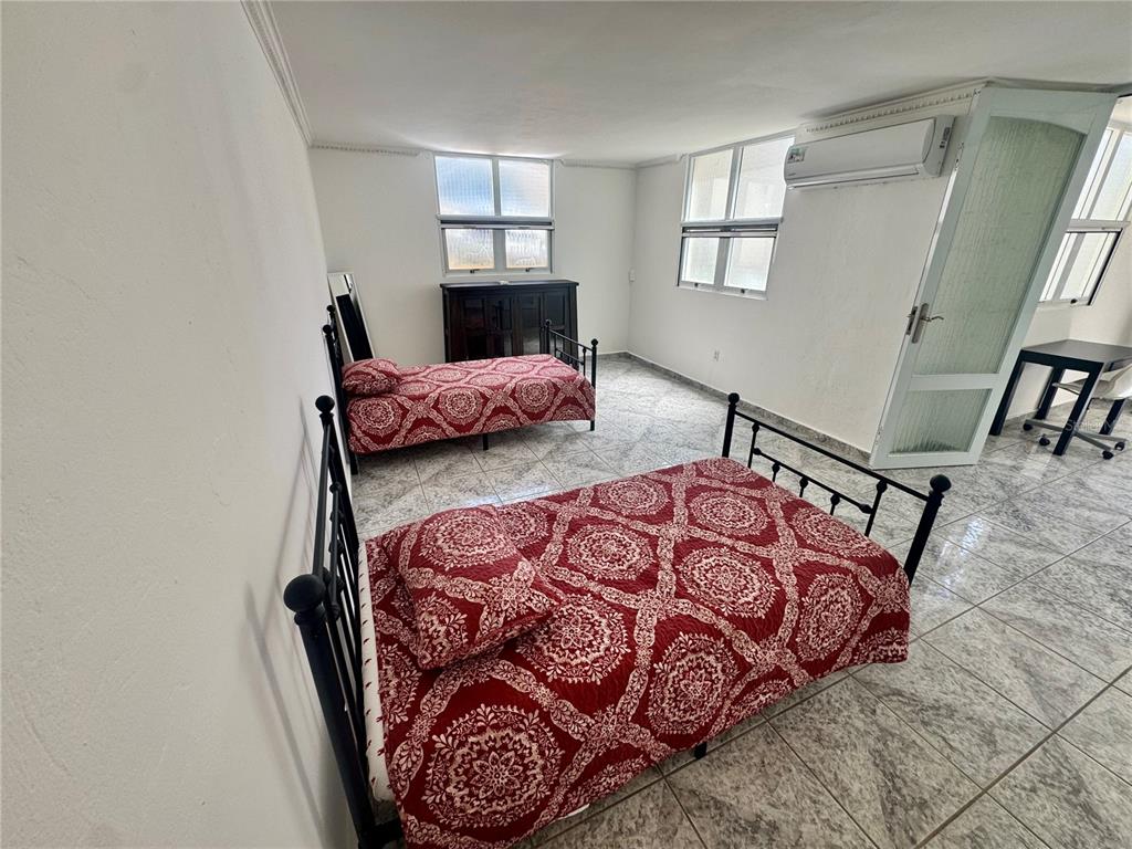 A bedroom with two beds, tiled floors, white walls, and a wall-mounted air conditioner — 125 HARBOUR DRIVE UNIT 8, HUMACAO, PR