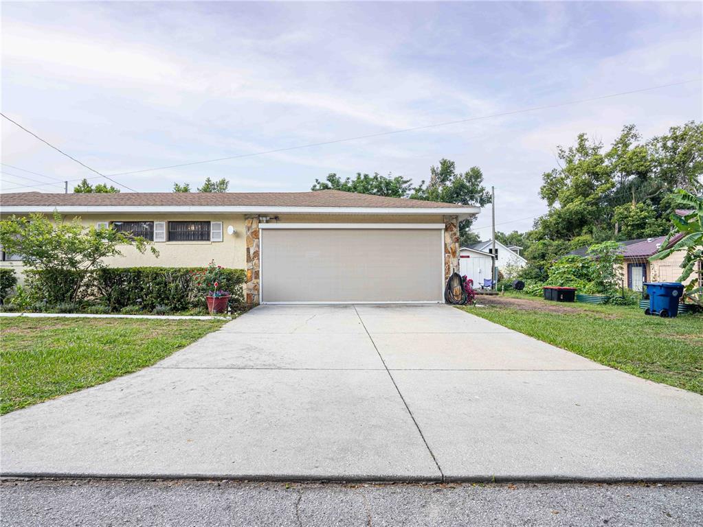 A single-story house with a beige exterior, a two-car garage, and a concrete driveway — 200 S MAIN AVENUE, MINNEOLA, FL