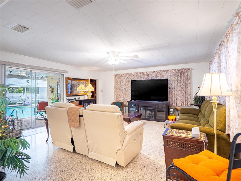 A living room features a beige recliner, a green sofa, a television, and a pool view — 200 S MAIN AVENUE, MINNEOLA, FL