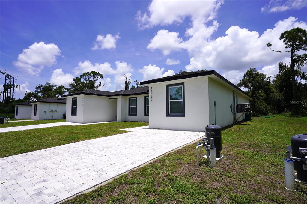 A white single-story house with a paved driveway and a well tank in the yard — 17070 BYRON AVENUE UNIT 17072, PORT CHARLOTTE, FL