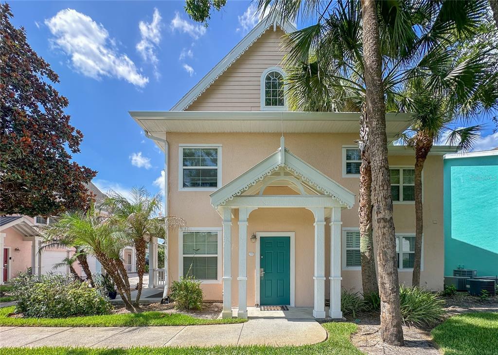 A two-story peach-colored house features a teal front door and a covered entryway porch — 5000 MANGROVE ALLEY UNIT 104, KISSIMMEE, FL
