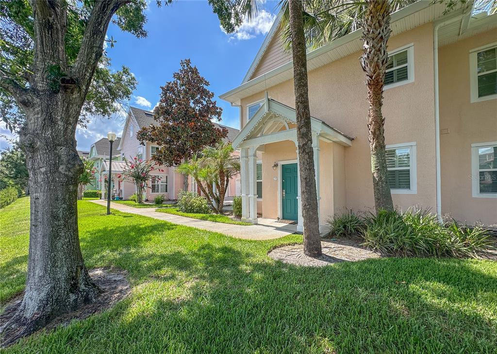 A two-story peach-colored townhouse with a teal front door and a covered entryway — 5000 MANGROVE ALLEY UNIT 104, KISSIMMEE, FL