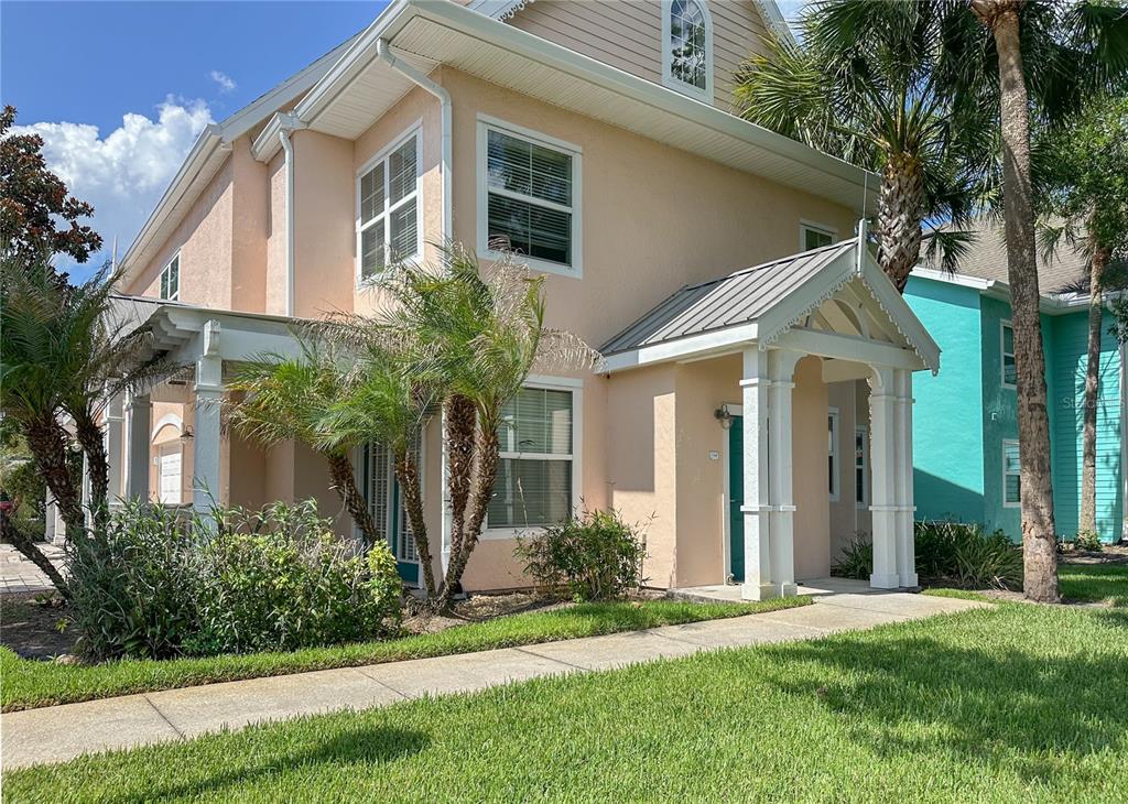 A two-story peach-colored house with a covered front porch and a metal roof — 5000 MANGROVE ALLEY UNIT 104, KISSIMMEE, FL