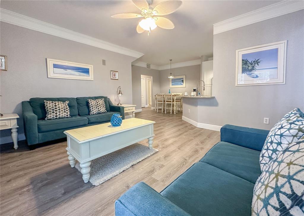 A living room with blue sofas, a light-colored coffee table, and an adjacent dining area — 5000 MANGROVE ALLEY UNIT 104, KISSIMMEE, FL